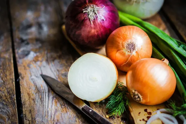 Červená žlutá cibule nakrájená nůžko zelené stonky na dřevě