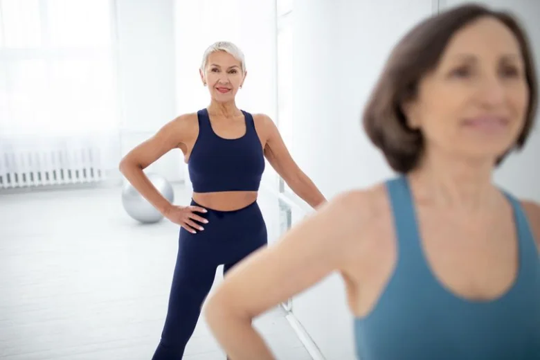Dvě seniorky v sportovním oblečení se usměvavě dívají na kameru.
