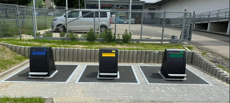 Tři barevně označené kontejnery na třídění odpadu venku.