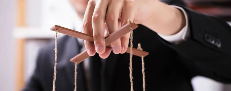 Ruka drží tyčinky s lankem jako marioneta pro manipulaci