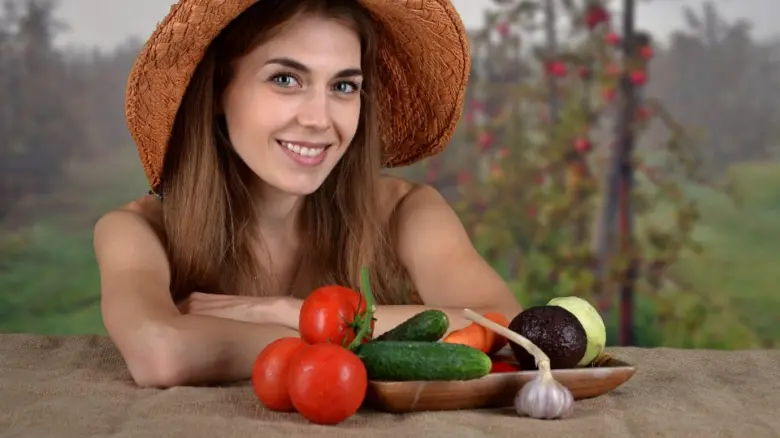 Žena s čerstvými zeleninovými produkty na venkovském pozadí.