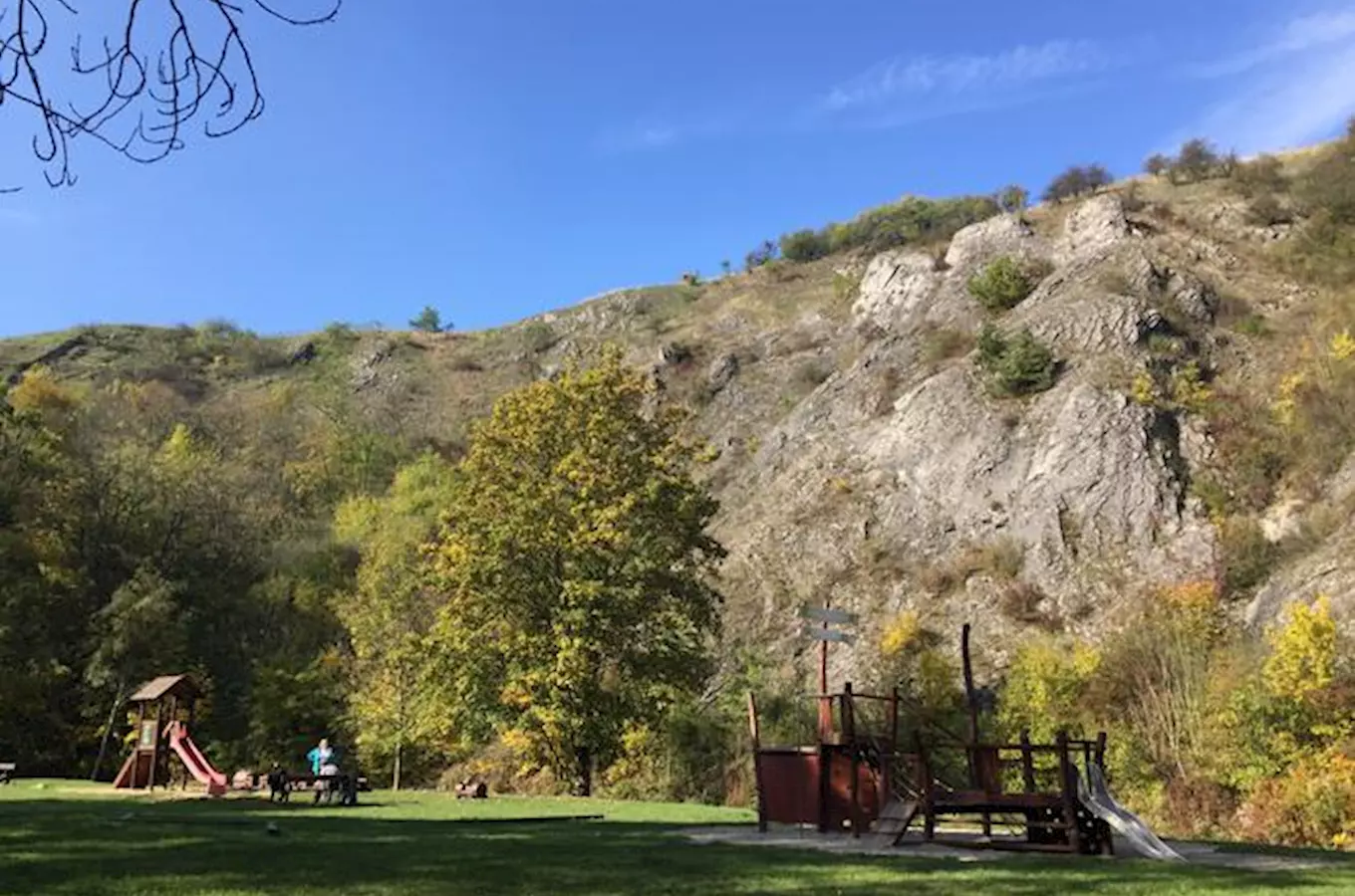 Hřiště v Prokopském údolí s hradbami a skalnatým svahem.