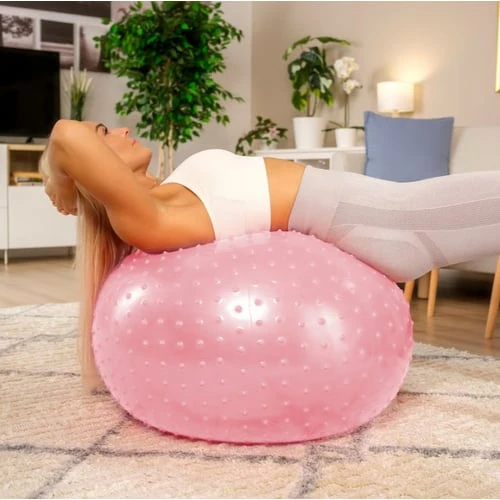 Žena cvičí na růžovém fitbalu pro posílení bederní páteře.