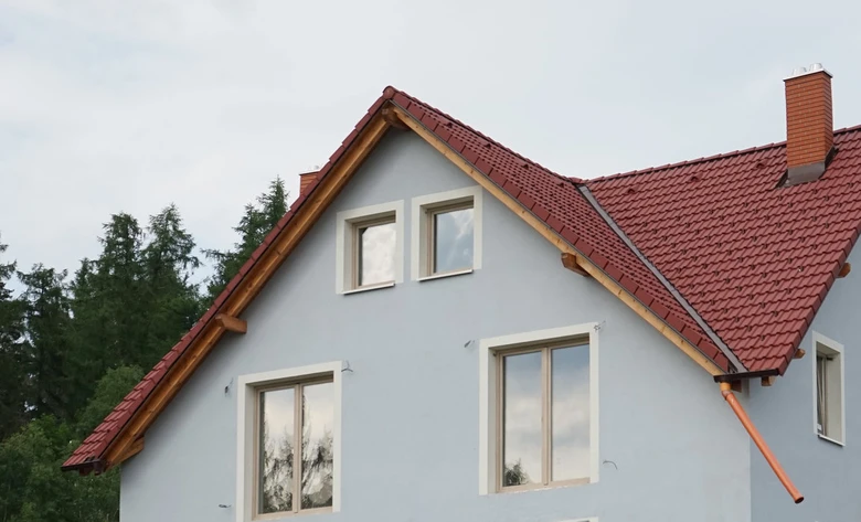 Modrý dům s červenou střechou ukazuje sklon střešního krytu.