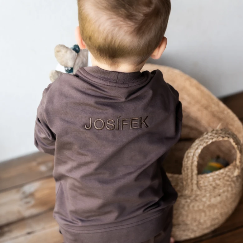 Dětský chlapec v tričku s jménem Josífek drží hrašku.