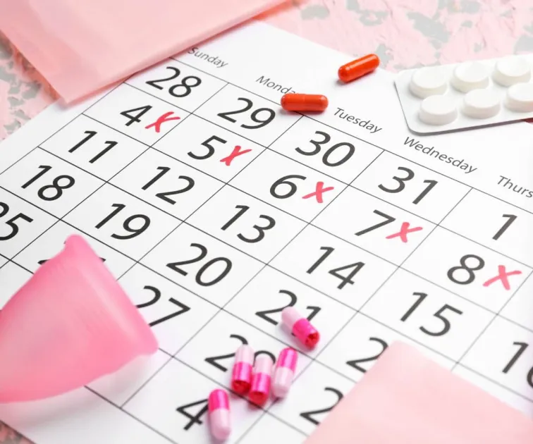 Kalendář s označenými zpožděnými menstruacemi a hygienickými prostředky.
