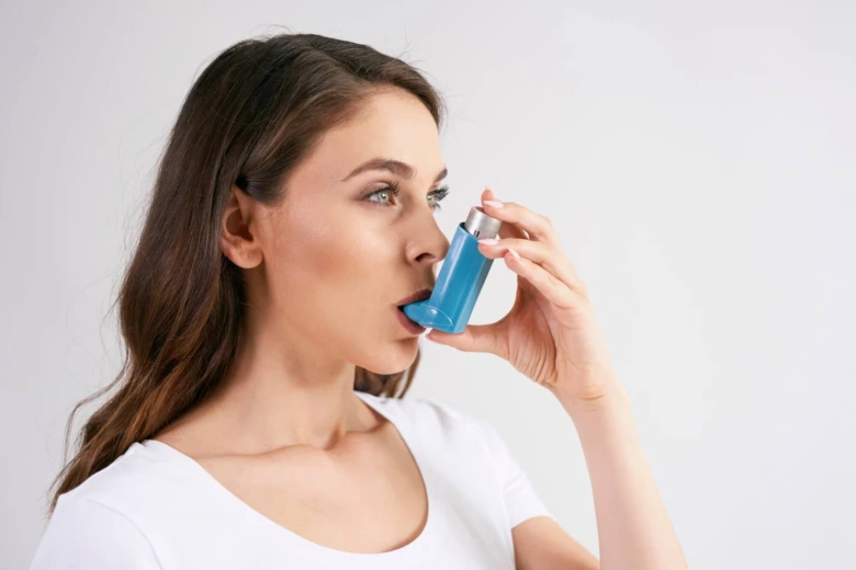 Žena správně používá modrý inhalátor pro astma.