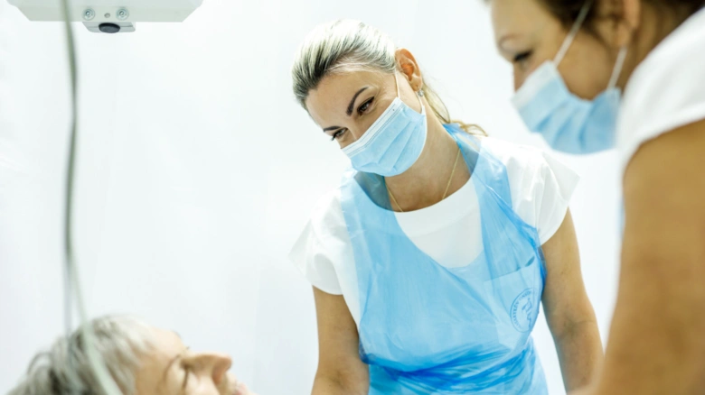 Lékaři v ochranném oblečení vyšetřují pacienta na klinice.