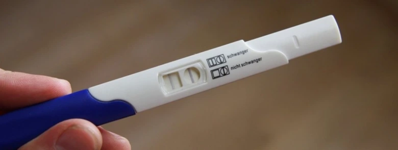 Těhotenský test s dvěma čarami naznačující těhotenství.