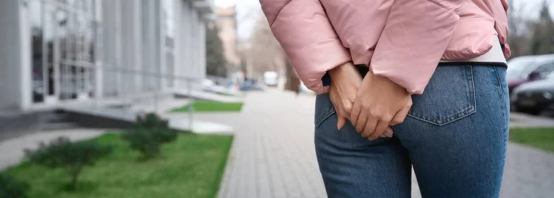 Osoba drží ruce na zadku v ulici.