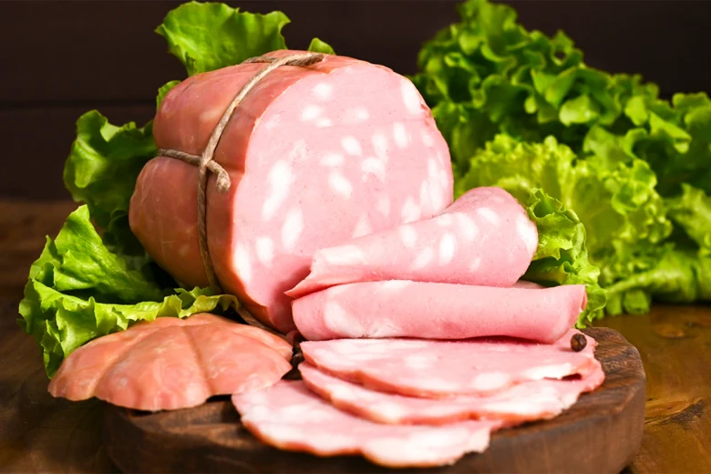Kus mrtadely s listím salátem na dřevěném talíři.