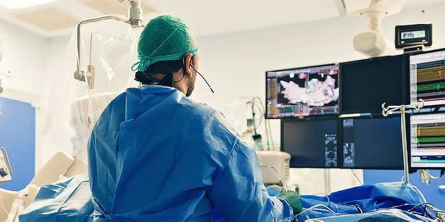 Chirurg v operační místnosti sleduje monitor s EKG.