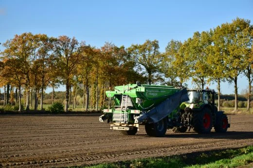 Traktor rozstřikuje hnojivo na připravené pole.