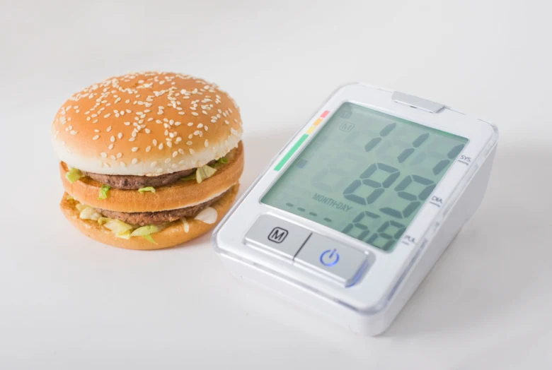 Burger vedle měřiče krevního tlaku ukazuje vliv stravy.