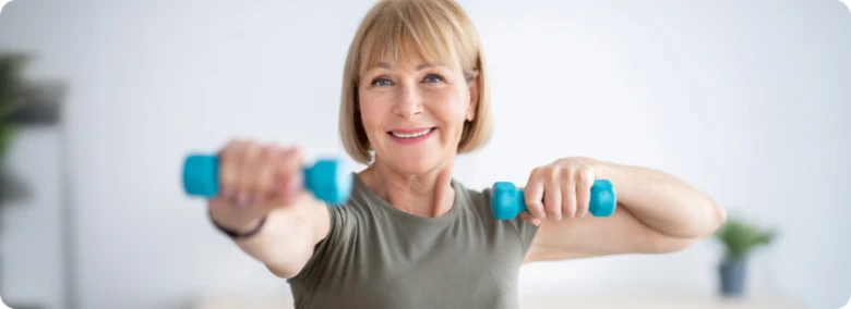 Starší žena zvedá činky při cvičení pro hubnutí v menopauze.