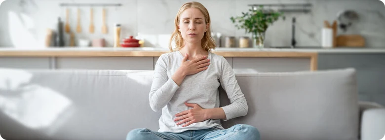 Žena sedí na gauči v kuchyni a praktikuje meditaci pro úzkost.