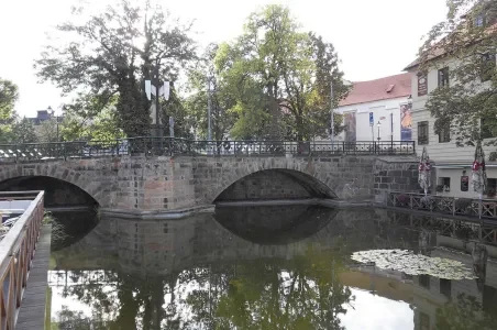 Kamenný most přes řeku v Plzni s odrazem ve vodě.