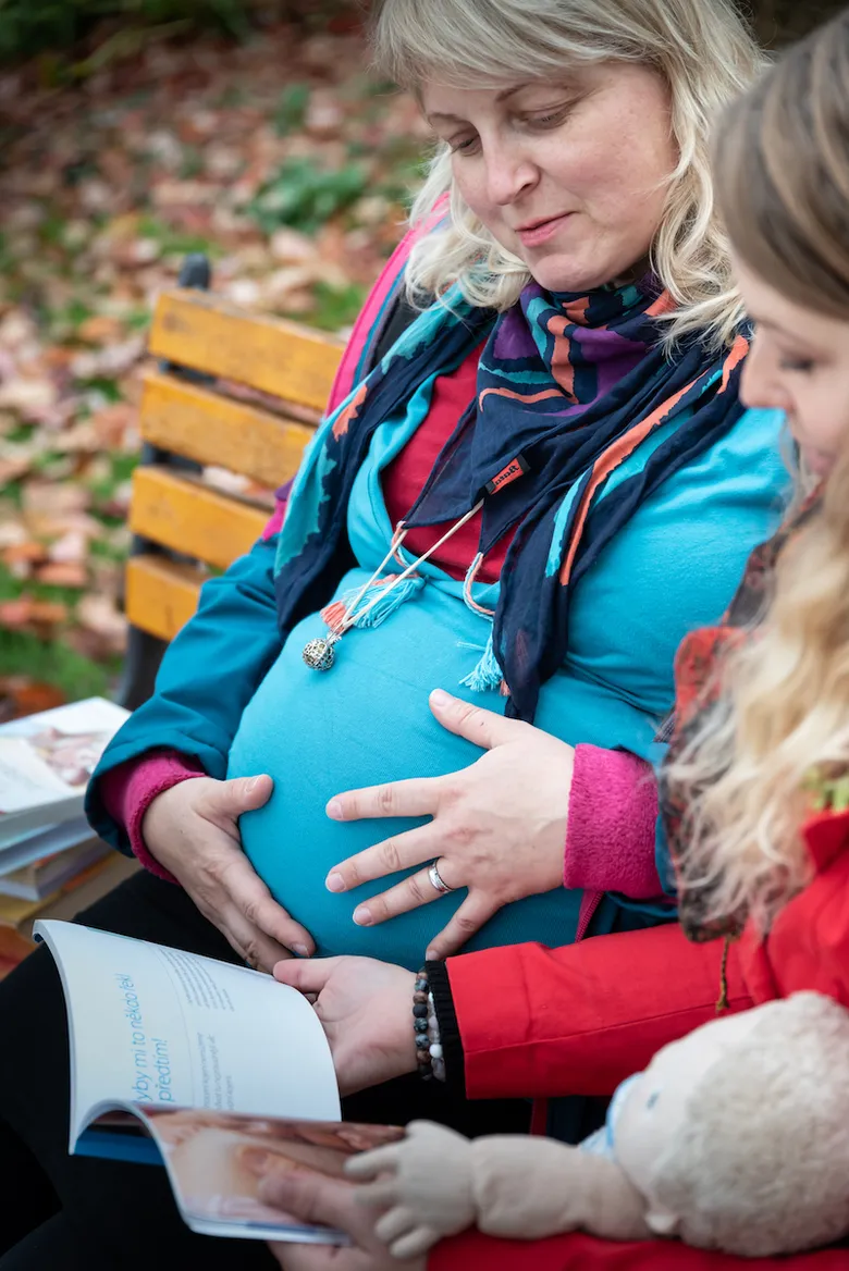 Těhotná žena s podporou dule při porodu venku