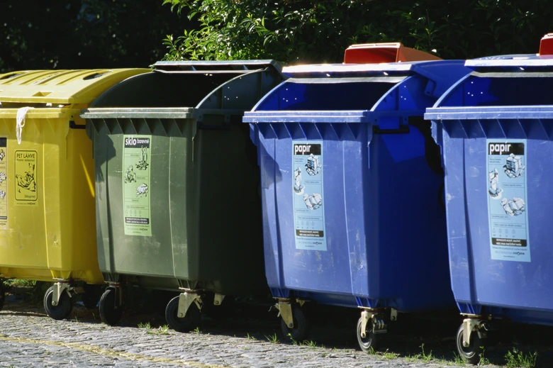 Řada barevných kontejnerů na recyklaci odpadů venku.