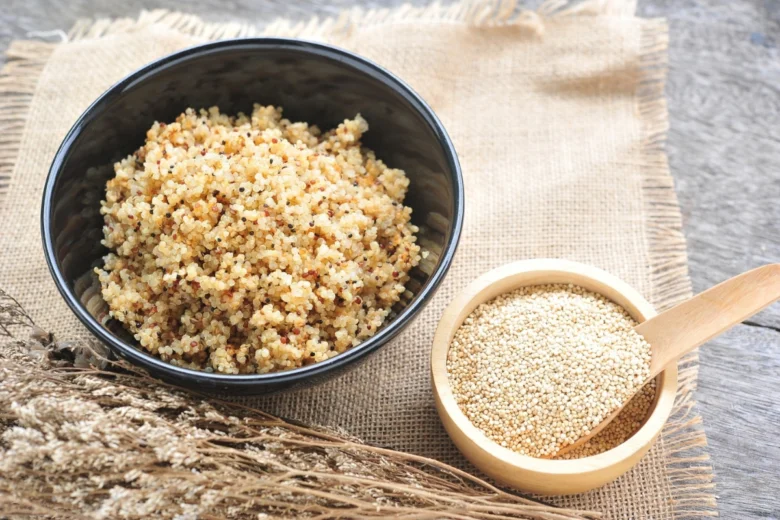 Uvařená a surová quinoa v miskách na lněném plátne.