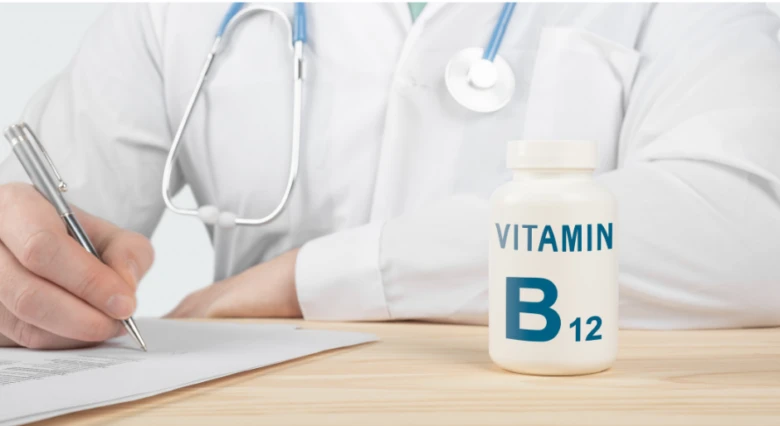 Lékař píše u stolu vedle lahvičky vitamínu B12.