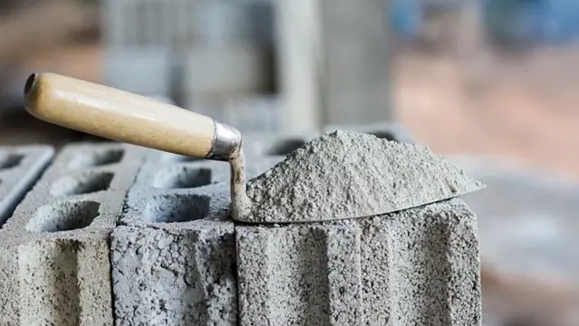 Mokrá maltová směs na stavební lopatce položené na cihlách.