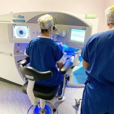 Dva lékaři operují oční lasery na moderním přístroji.