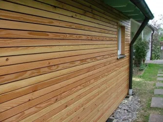 Zdivo domu obložené dřevěnými prkny na fasádě.