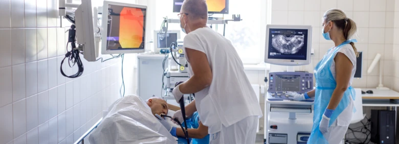 Lékař vyšetřuje pacienta v nemocničním prostředí s ultrazvukovými monitory.