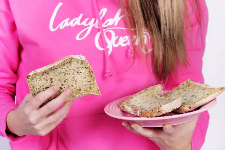 Dvě plátky celozrnného chleba s semínky na růžovém talíři.