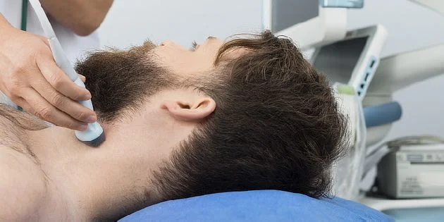 Muž podléhá ultrazvukovému vyšetření krku v ordinaci.