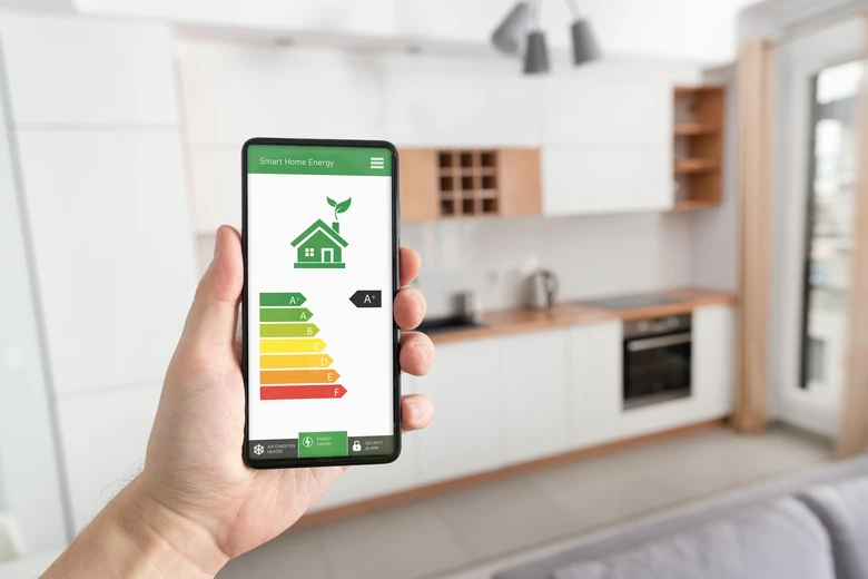 Smartfon s aplikací na sledování spotřeby energie v kuchyni.