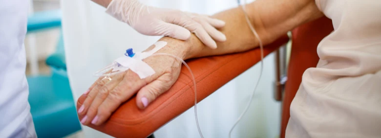 Zdravotník drží ruku pacienta při odběru krve v nemocnici.