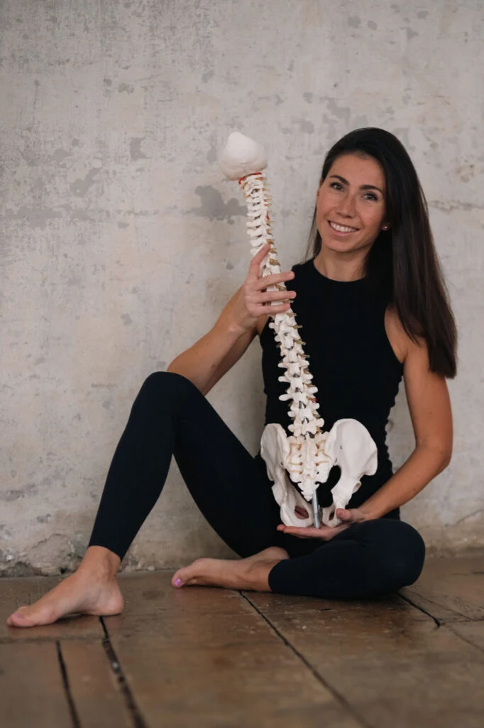 Žena drží model pánevního dna a obratle.