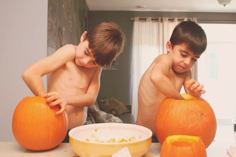 Děti čistí dýně pro výrobu svíčků na Halloween.