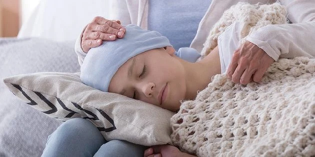 Dívka spí s rukou dospělého na hlavě, symbol péče.