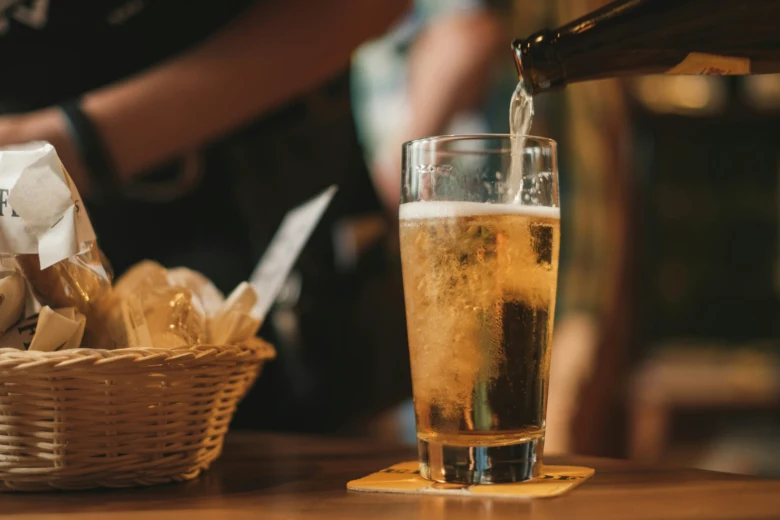 Pivo se nalévá do sklenice vedle košíku s chlebem.