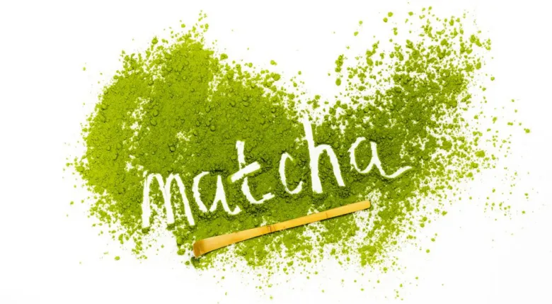 Prášek z zeleného čaje Matcha s bambusovým šlehačem na bílém pozadí.