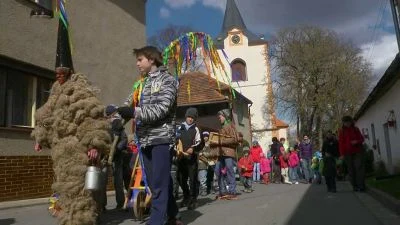 Lidé v kostýmech na velikonočním průvodu u kostela.