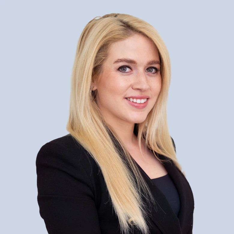 Portrétní fotografie blond ženy v černém obleku.