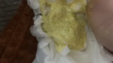 Světlá stolice dítěte v plenkách na hnědé utěrce.