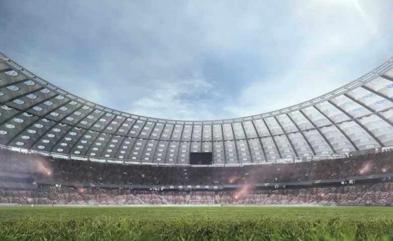 Vnitřek plného stadionu s trávníkem pod oblohou.