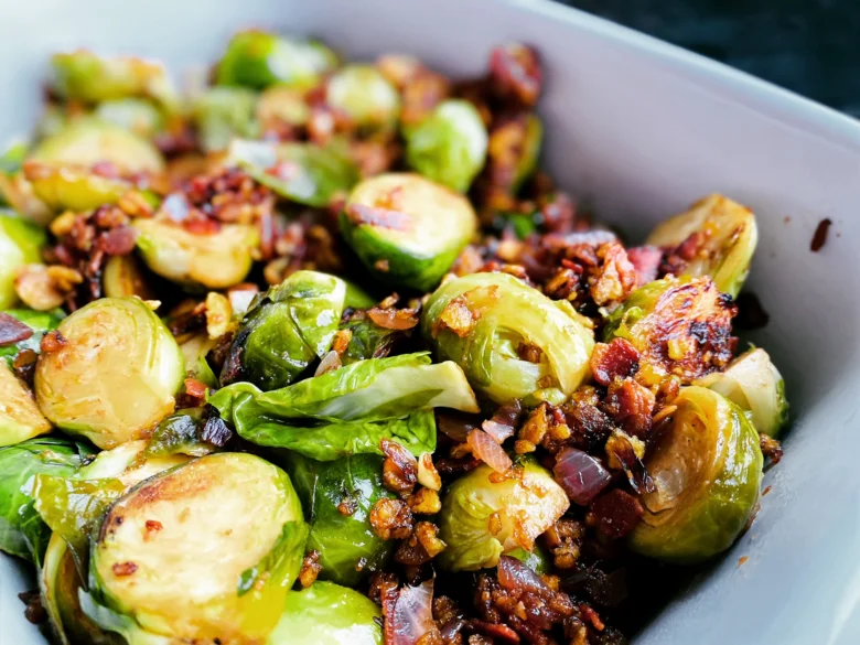 Pečené růžičkové kapusty s křupavým bůčkem a cibulkou v bílé misce.
