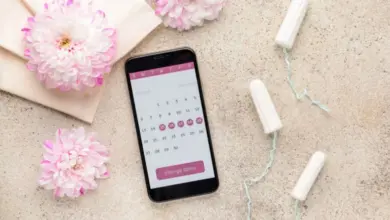Telefon s kalendářem menstruačního cyklu, vataky a květy.