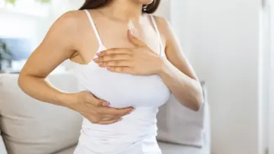 Žena drží prsa a břicho kvůli bolesti na dotek.