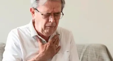 Muž drží ruku na hrudi kvůli bolesti.