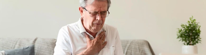 Muž drží ruku na hrudi kvůli bolesti.