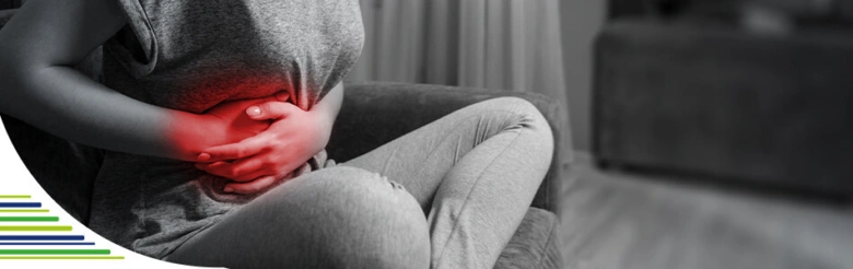 Žena drží břicho v bolesti kvůli podrážděnému žlučníku.