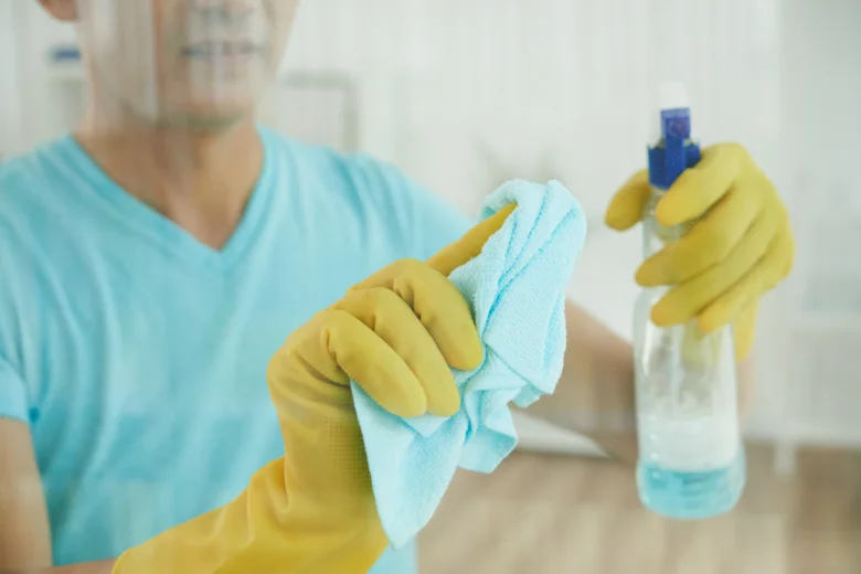 Muž v rukavicích čistí povrch hadříkem s čisticím prostředkem.