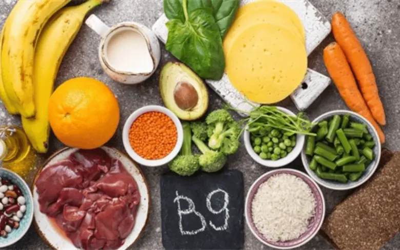 Různé potraviny bohaté na vitamin B9 uspořádané kolem tabule s nápisem B9.